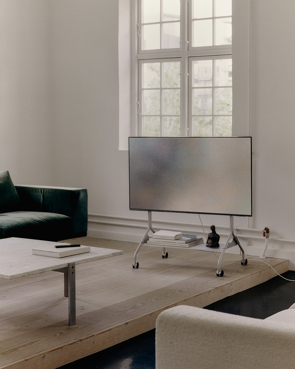 Moon in Cloudy Silver avec TV dans un salon lumineux, support à roulettes sur estrade en bois, vue de face